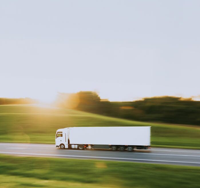 pexels photo 18290480 White cargo truck speeding through Vitebsk countryside at sunrise, symbolizing transportation and logistics.