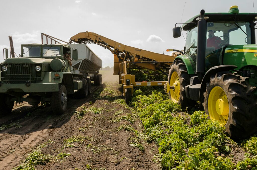 pexels photo 2255801 2255801 A tractor and truck collaborate in harvesting crops on a sunny farm field.