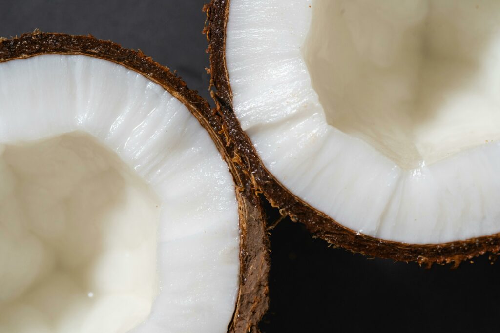 pexels photo 7676877 7676877 Detailed close-up of fresh coconut halves showing white kernel and rough shell.